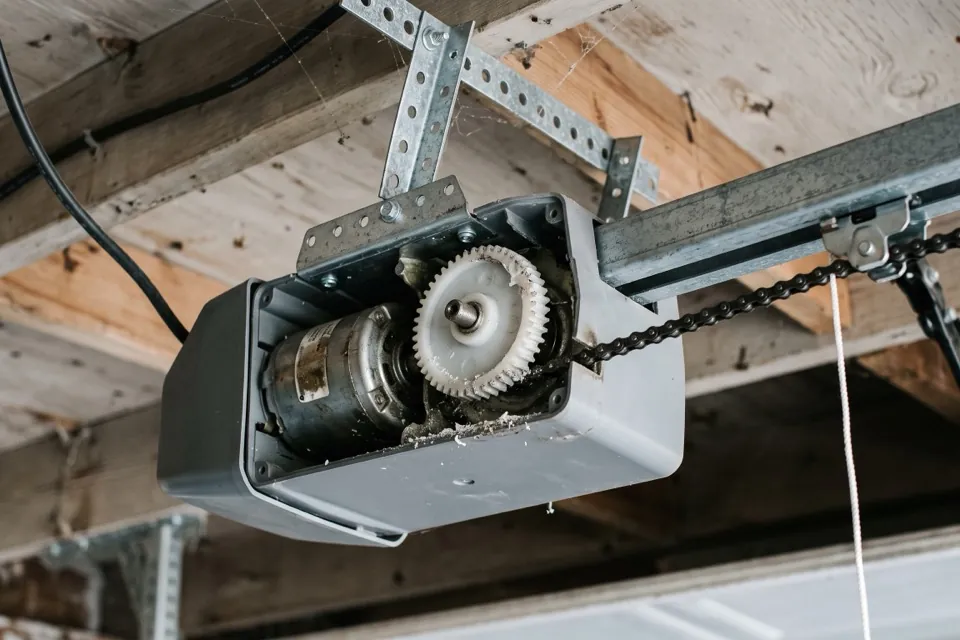 A garage door opener motor head opened up with the nylon drive gear exposed